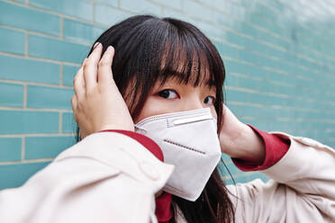 Frau hält sich die Ohren zu und trägt eine Gesichtsmaske - ASGF00961