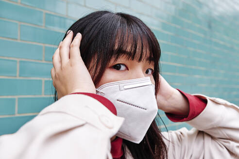 Woman covering ears while wearing protective face mask - ASGF00961