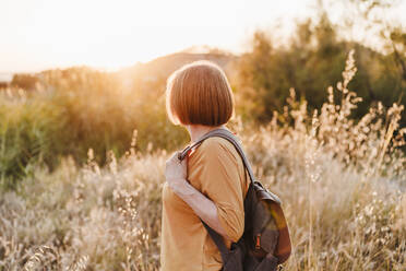 Woman looking at sunset while hiking - EBBF04432