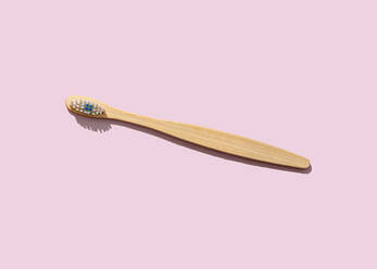 Studioaufnahme einer hölzernen Zahnbürste vor einem rosa Hintergrund - FLMF00628