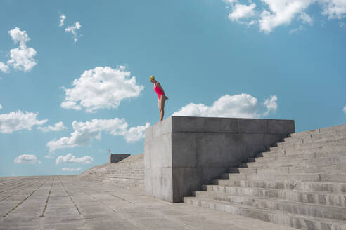 Woman looking down at concrete footpath during sunny day - VPIF04430