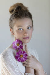 Junge Frau mit lilafarbenen Blumen, die im Atelier nachdenkt - EIF01809