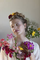 Young woman with multi colored wildflowers in front of white background - EIF01812