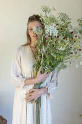 Junge Frau hält einen Strauß Wildblumen im Atelier - EIF01832