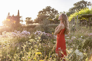 Young woman standing in flowers field - EIF01866