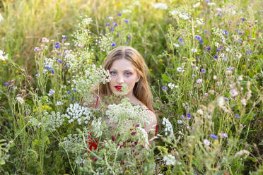 Schöne Frau inmitten von Wildblumen auf einem landwirtschaftlichen Feld - EIF01870