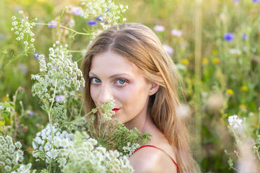 Schöne junge Frau mit Wildblumen im Feld - EIF01871