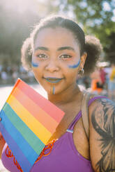 Young woman with rainbow flag on sunny day - MEUF03664