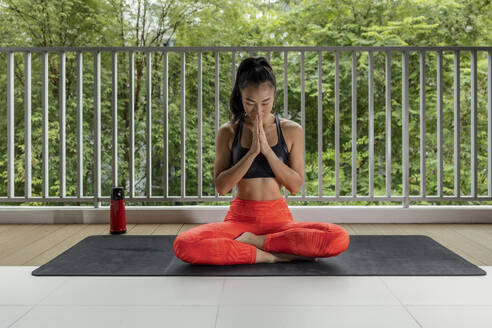 Sportswoman with hands clasped meditating at balcony - EAF00029