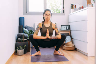 Junge Frau meditiert beim Yoga zu Hause - DAMF00867