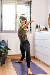 Frau benutzt Virtual-Reality-Headset beim Training zu Hause - DAMF00884