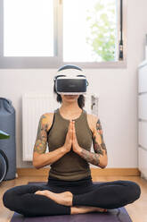 Frau meditiert mit einem Virtual-Reality-Headset zu Hause - DAMF00887