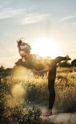 Mid adult woman balancing while doing yoga at countryside - DAMF00889