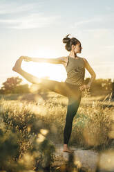 Woman with hand on hip doing stretching exercise at countryside - DAMF00892