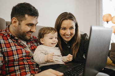 Glückliche Familie während eines Videoanrufs über den Laptop zu Hause - GMCF00234
