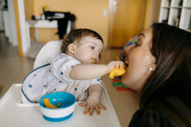 Baby boy feeding mother at home - GMCF00240