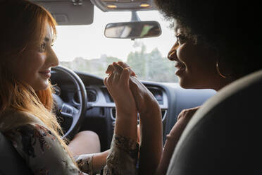 Lächelnde Freundinnen, die sich im Auto an den Händen halten - JCCMF03410