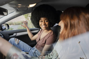 Afro-Frau lächelnd mit Blick auf Freundin im Auto - JCCMF03414
