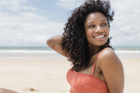 Lächelnde schöne Frau, die an einem sonnigen Tag am Strand wegschaut - JRVF01270
