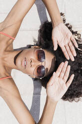 Frau mit Sonnenbrille beim Sonnenbaden am Strand - JRVF01274