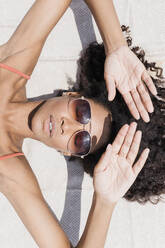 Woman wearing sunglasses sunbathing at beach - JRVF01274