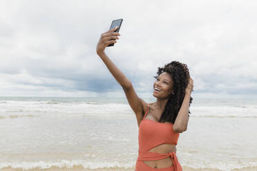 Happy beautiful woman taking selfie through mobile phone at beach - JRVF01303