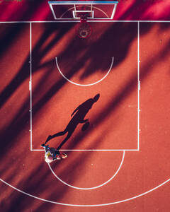 Luftaufnahme des Schattens eines Basketballspielers auf einem Platz im Freien in Kaunas, Litauen. - AAEF12727