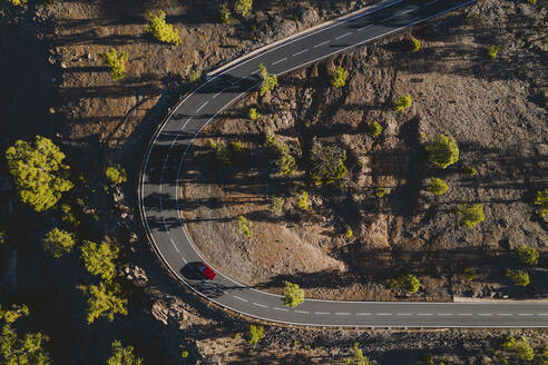 Luftaufnahme eines roten Fahrzeugs auf einer kurvenreichen Bergstraße in Teneriffa, Kanarische Inseln, Spanien. - AAEF12771