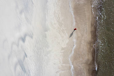 Luftaufnahme einer Person, die am Strand in der Nähe der Ostsee in Klaipeda, Litauen, spazieren geht. - AAEF12841