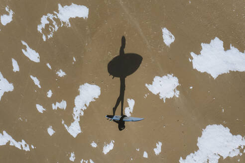 Luftaufnahme von Surfer Silhouette Schatten zu Fuß auf dem Strand im Winter in Klaipeda, Litauen. - AAEF12854
