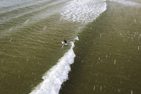 Luftaufnahme eines Surfers, der auf die Wellen in der Ostsee während eines Schneesturms im Frühling wartet, Klaipeda, Litauen. - AAEF12858