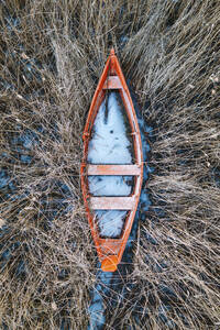 Luftaufnahme eines alten Holzbootes, das zwischen Schilf im Wintersee eingefroren ist, Trakai, Litauen. - AAEF12885