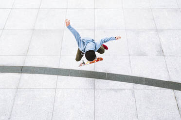 Aerial view of professional skateboarder doing a kick flip trick in urban background in central square in Kaunas city, Lithuania. - AAEF12907