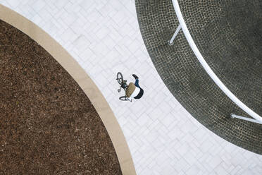 Aerial view of BMX rider doing a trick in public area in city center in Panevezys, Lithuania. - AAEF12930