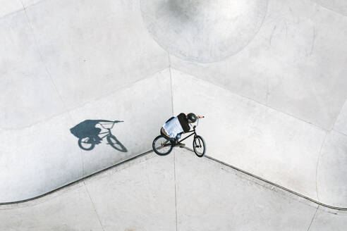 Aerial view of BMX bike rider doing a jump and bar turn trick in local skatepark near Panevezys, Lithuania. - AAEF12937