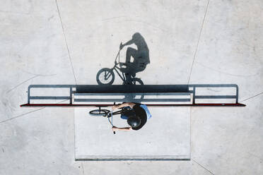 Aerial view of BMX bike rider silhouette shadow grinding rail in outdoor skatepark near Panevezys, Lithuania. - AAEF12944