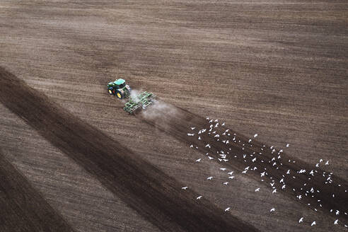 Luftaufnahme eines Traktors beim Eggen eines landwirtschaftlichen Feldes im Frühling, Kaunas, Litauen. - AAEF12981