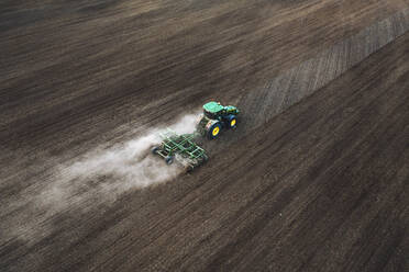 Luftaufnahme eines Traktors, der landwirtschaftliche Flächen bearbeitet, um sie für den Ackerbau vorzubereiten, auf dem Land in der Nähe von Kaunas, Litauen. - AAEF12987