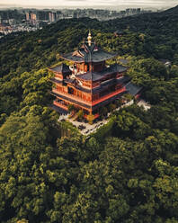 Luftaufnahme eines buddhistischen Tempels auf dem Gipfel eines Hügels im Wald bei Sonnenaufgang, Hangzhou, China. - AAEF13065