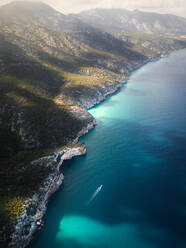 Luftaufnahme eines Motorboots, das entlang der wilden Küste mit Klippen am Mittelmeer in Cala Gonome, Sardinien, Italien, fährt. - AAEF13142