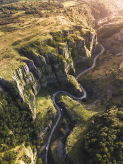 Luftaufnahme einer Panoramastraße, die sich durch eine Schlucht in der Cheddar-Schlucht, einer tiefen Kalksteinfelsformation, im Vereinigten Königreich schlängelt. - AAEF13148