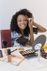 Smiling female make-up artist brushing eyebrows in studio - JRVF01312