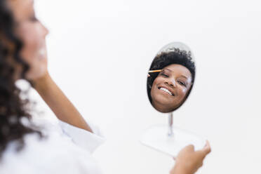 Woman applying eyeshadow while looking at mirror reflection - JRVF01322