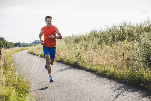 Männlicher Sportler beim Laufen auf der Straße - UUF24246