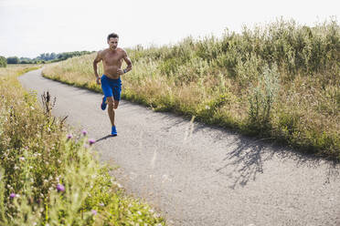 Shirtless male athlete running on road - UUF24251