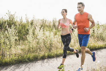 Sports people running together during sunny day - UUF24256