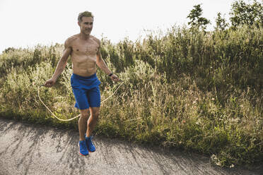 Shirtless reifen Mann üben Seil springen auf der Straße - UUF24269