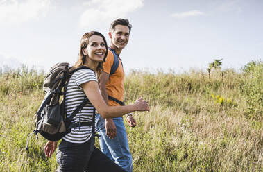 Happy woman hiking with man at meadow - UUF24282