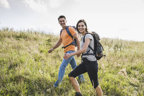 Smiling woman walking by man on grass - UUF24283