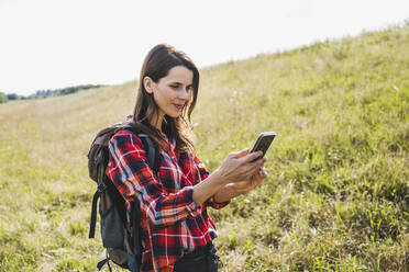 Female hiker using mobile phone at meadow - UUF24284